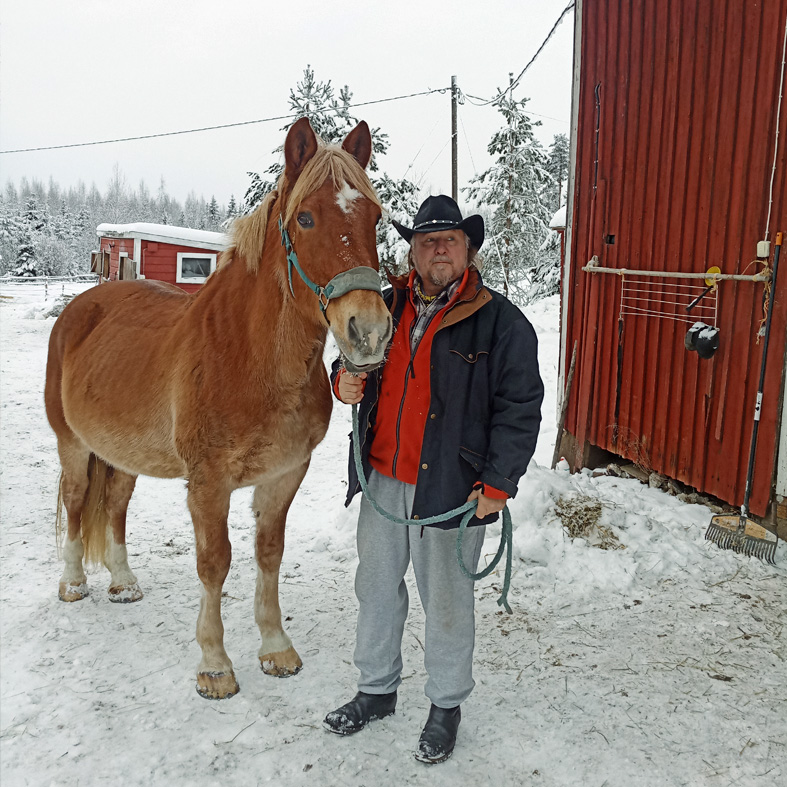 Kuvassa ulkona seisomassa Jouni Kilpi ja vaaleanruskea Mokkasiini suomenhevonen. Taustalla punaisia rakennuksia.