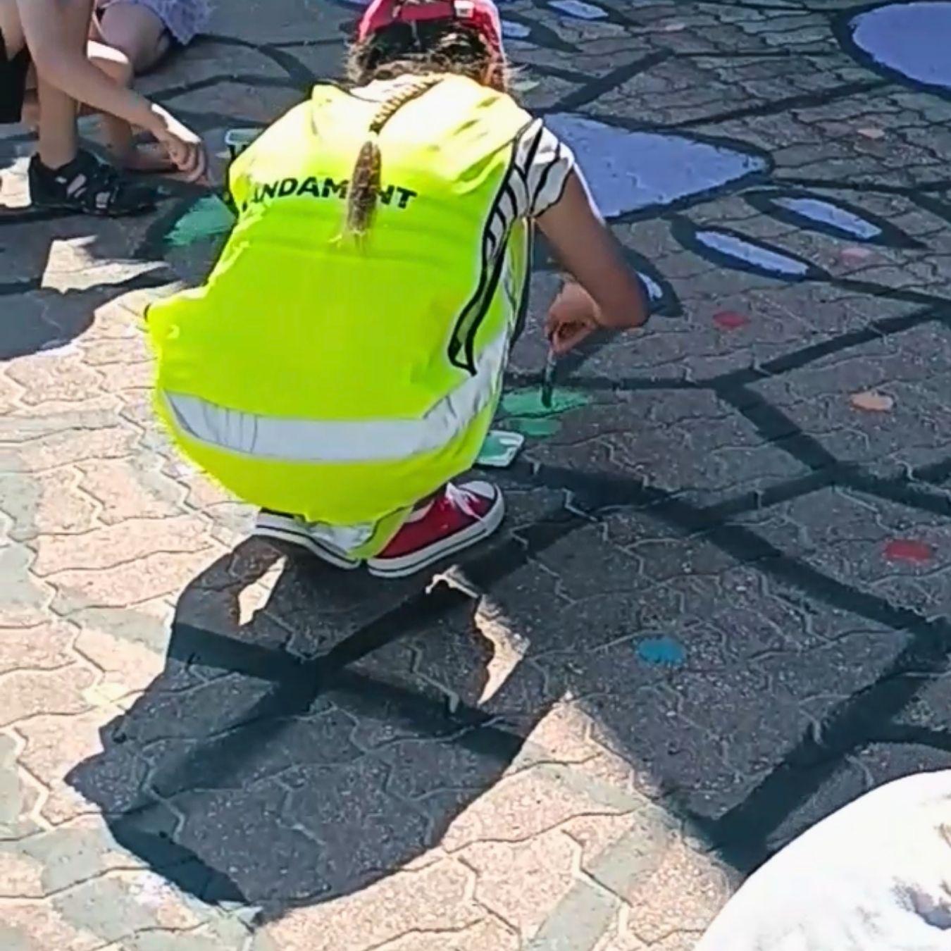 Lapsi maalaa katumaalausta kyykyssä.